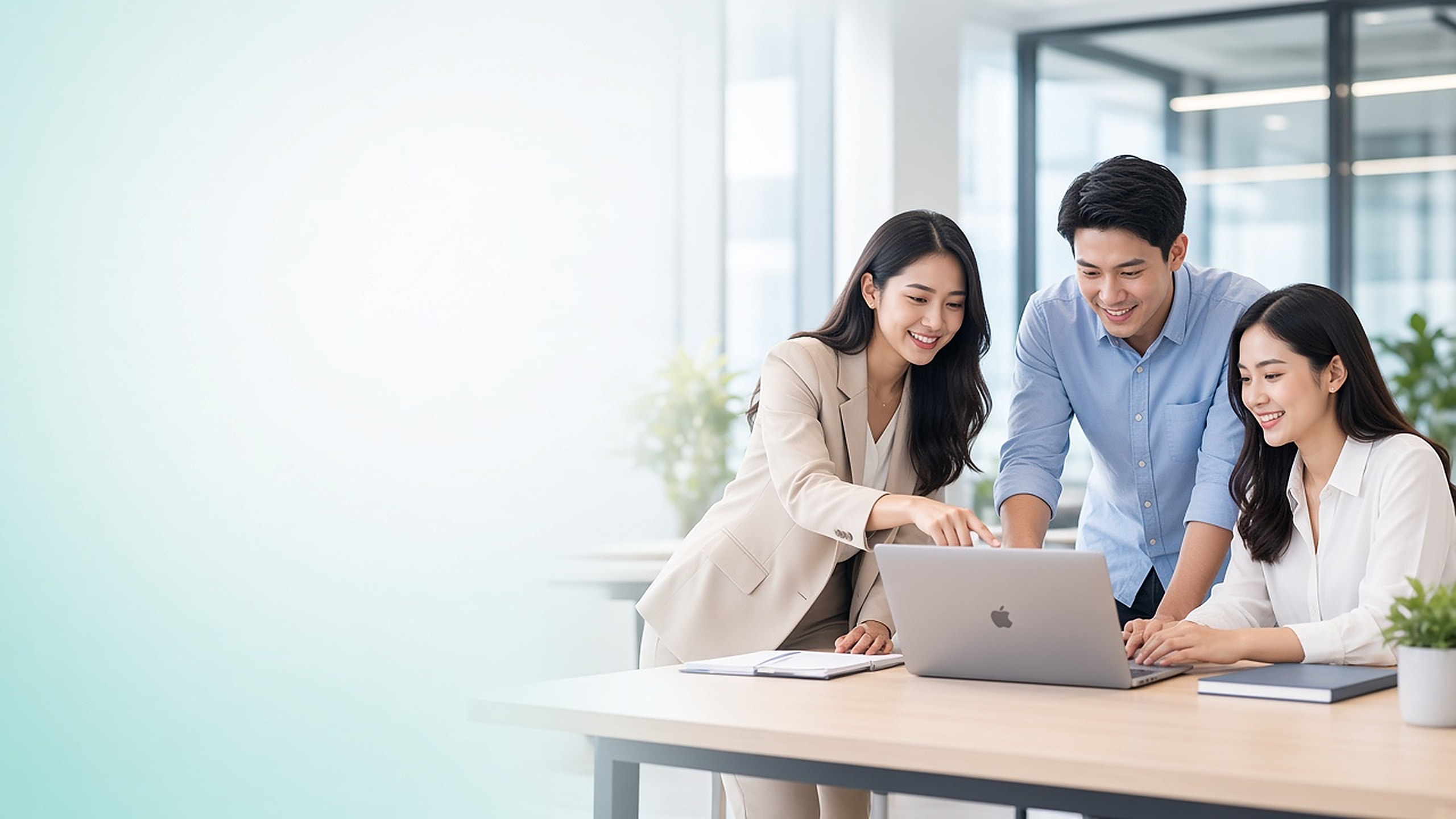 Tim sedang bekerja bersama di depan laptop di kantor yang terang.